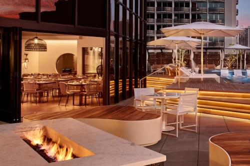a patio area with tables, chairs and umbrellas at Hyatt Centric Waikiki Beach in Honolulu
