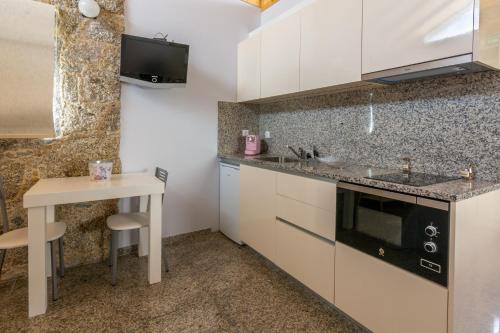 a kitchen with white cabinets and a small table at Aldeamento Casas do Alto do Vez in Balouta