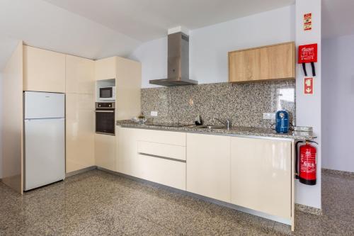 a kitchen with white cabinets and a refrigerator at Aldeamento Casas do Alto do Vez in Balouta
