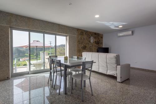 a dining room with a table and chairs and a couch at Aldeamento Casas do Alto do Vez in Balouta