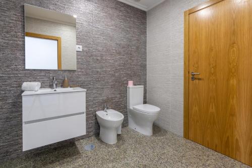 a bathroom with a toilet and a sink and a mirror at Aldeamento Casas do Alto do Vez in Balouta