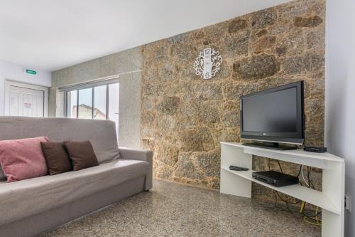 a living room with a couch and a tv at Aldeamento Casas do Alto do Vez in Balouta