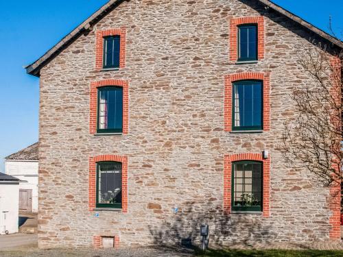 una antigua casa de piedra con ventanas de ladrillo rojo en Pretty Farmhouse in Houffalize with Courtyard, en Houffalize