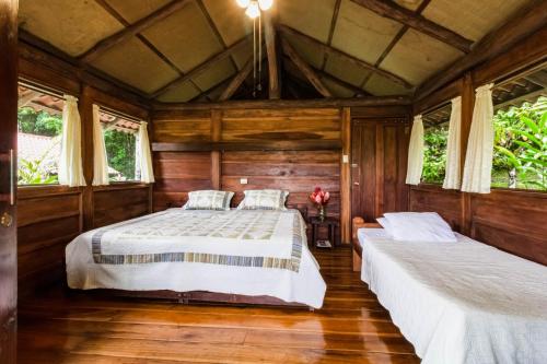 two beds in a room with wooden walls and windows at La Anita Rain Forest in Colonia Dos Ríos