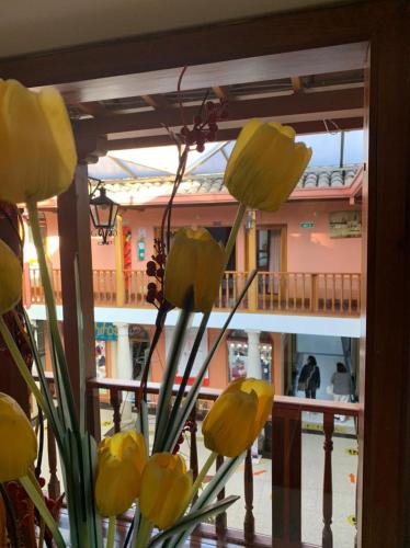 a vase with yellow flowers in front of a building at Hotel El Cid Plaza Premium in Tunja