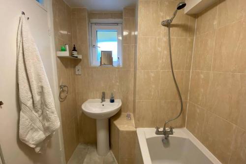 ein Badezimmer mit einem Waschbecken, einem WC, einer Badewanne und einem Waschbecken in der Unterkunft Two Bedroom Garden Flat in Zone 2 London in London