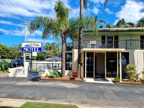 a motel sign in front of a building with palm trees at Ocean Parade Motel in Coffs Harbour