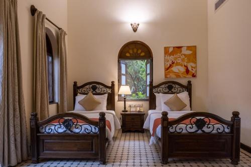 a bedroom with two beds and a window at Mercure Goa Devaaya Resort in Old Goa