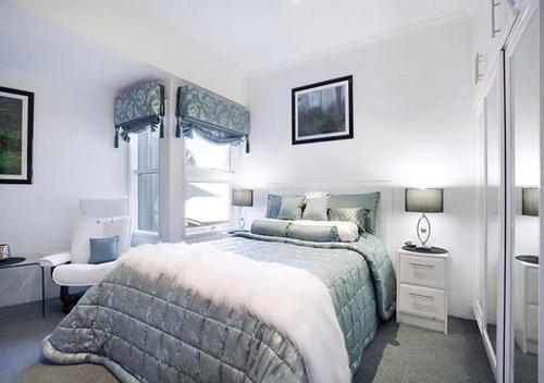 a white bedroom with a large bed and a chair at Snowgums 15 in Dinner Plain