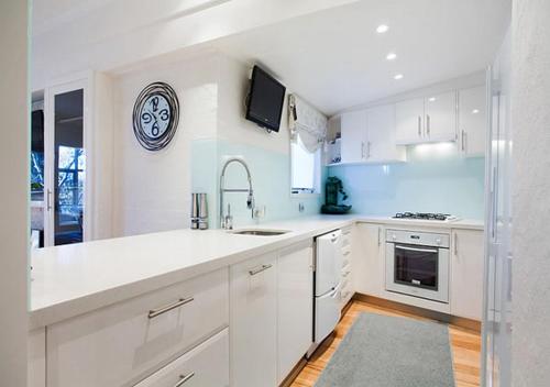 a white kitchen with white cabinets and a sink at Snowgums 15 in Dinner Plain