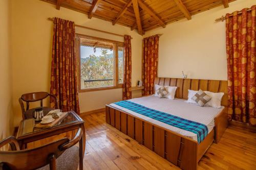 a bedroom with a bed and a desk and a window at StayVista at Brij Valley with Indoor Games & Bonfire in Rāmgarh