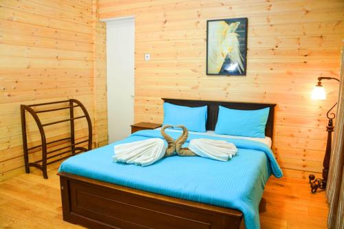 a bedroom with a blue bed with a wooden wall at Little England Bungalow in Nuwara Eliya