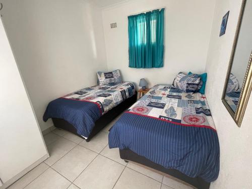 1 dormitorio con 2 camas y una ventana con cortinas verdes en 127 Hermanus Beach Club, en Hermanus
