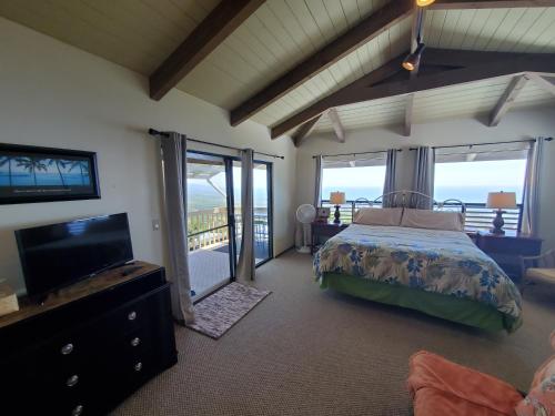 a bedroom with a bed and a flat screen tv at A Beautiful Edge of the World Bed & Breakfast in Captain Cook