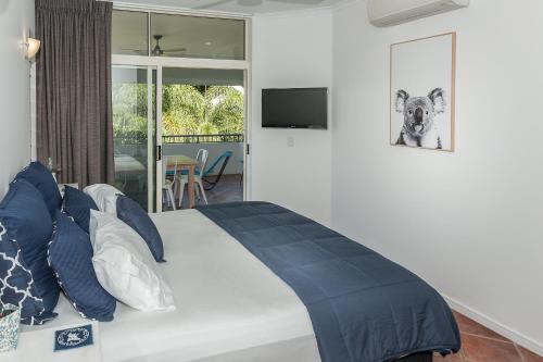 a bedroom with a large bed with blue pillows at Oasis at Palm Cove in Palm Cove