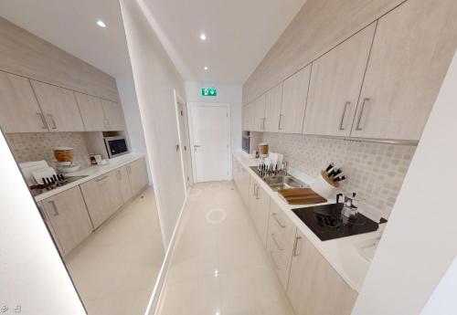 a white kitchen with white cabinets and a sink at Seven - West Beach - The Palm Jumeirah, Dubai in Dubai