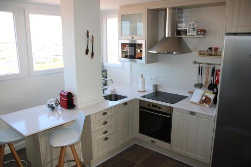 uma cozinha com armários brancos e um frigorífico preto em Precioso apartamento con magníficas vistas - Apartamento Aifos em Santander