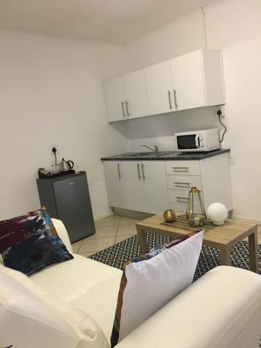ein Wohnzimmer mit einem weißen Sofa und einer Küche in der Unterkunft Omaha Luxury B&B/Spa in Mthatha