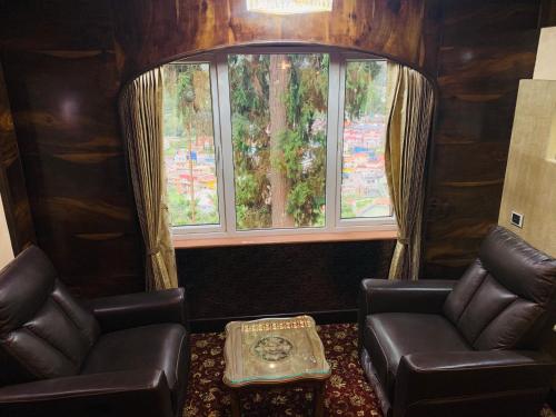 a living room with two chairs and a window at Beverly villa in Ooty