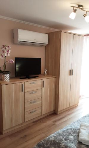 a living room with a flat screen tv on a wooden cabinet at Jázmin Apartman in Tihany