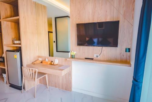 a room with a table and a television on a wall at Phuengluang Riverside Hotel Chanthaburi in Chanthaburi