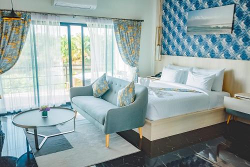 a bedroom with a bed and a chair and a table at Phuengluang Riverside Hotel Chanthaburi in Chanthaburi