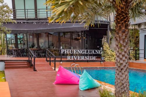 two pink and blue bags sitting next to a swimming pool at Phuengluang Riverside Hotel Chanthaburi in Chanthaburi