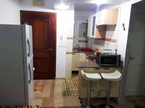 a kitchen with a refrigerator and a counter with stools at S+2 zone touristique Mahdia in Hiboun