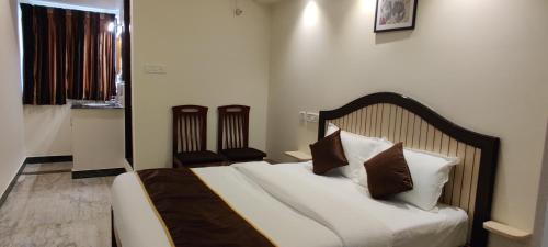 a bedroom with a bed with white sheets and brown pillows at Rmc travellers inn in Chennai