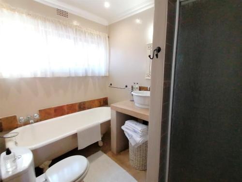 a bathroom with a tub and a toilet and a sink at Van Dykshuis Guest House in Heidelberg