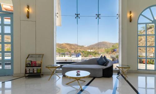 a living room with a couch and large windows at Ramee Royal Resort & Spa - Udaipur in Udaipur
