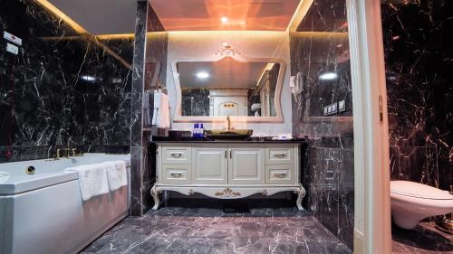 a bathroom with a tub and a toilet and a sink at Wyndham Batumi in Batumi