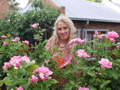a woman standing in a garden of pink roses at Van Dykshuis Guest House in Heidelberg