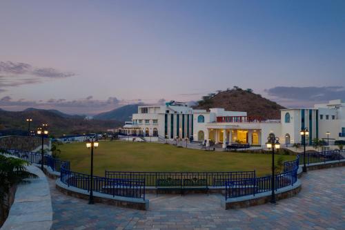 a group of buildings with lights and a grass field at Ramee Royal Resort & Spa - Udaipur in Udaipur