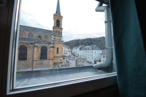 a view from a window of a church with a clock tower at la perle grise de la semois in Bouillon