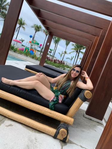 a woman sitting on a bed at a resort at SALINAS EXCLUSIVE RESORT in Salinópolis