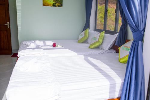 a large white bed with blue curtains in a room at SUNRISE HOTEL in Con Dao