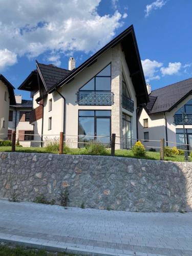 a large white house with a stone wall at Vila S6 in Zlatibor