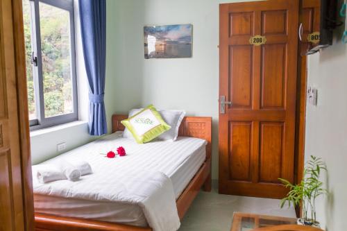 a small bedroom with a bed with red flowers on it at SUNRISE HOTEL in Con Dao