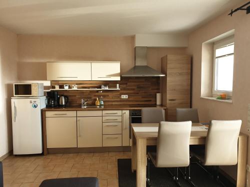 eine Küche mit einem Tisch und einem weißen Kühlschrank in der Unterkunft Fewo-Eifel-Morsbach in Schleiden