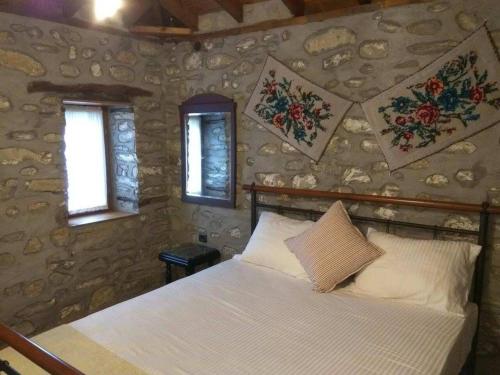 a bedroom with a bed with a stone wall at Petra House in Nikiti