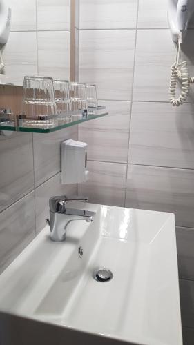 a bathroom with a sink and glasses on a shelf at Hotel Rózsa Csárda in Hegyeshalom
