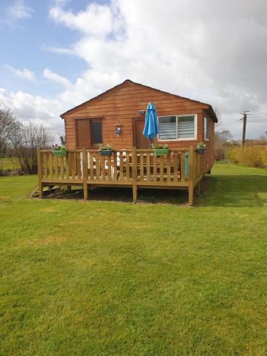 une cabane en rondins avec une terrasse et un parasol dans l'établissement Le Chal Adret, à Cardonville