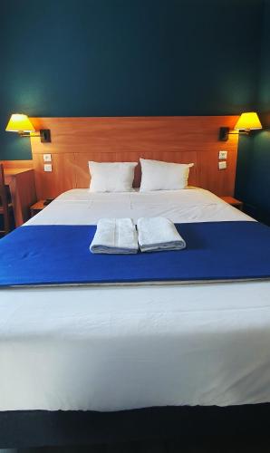 a large white bed with two towels on it at Glisy Hôtel in Glisy