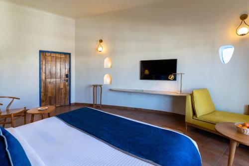 a bedroom with a bed and a couch and a tv at Ramee Royal Resort & Spa - Udaipur in Udaipur
