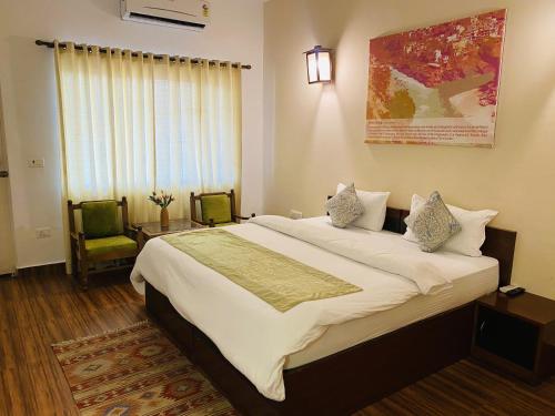 - une chambre avec un grand lit et deux chaises dans l'établissement Sanskriti Vedic Retreat, à Rishikesh