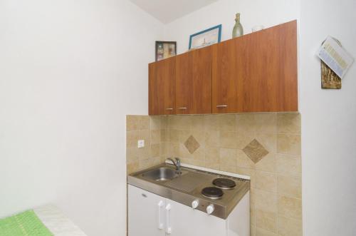a kitchen with a sink and wooden cabinets at Apartments Vitorin in Sobra