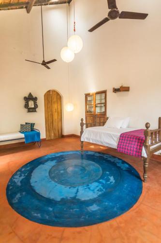 a large blue rug in a room with a bed at Seclude Falling Cashews, Chorao Island, North Goa in Chorao