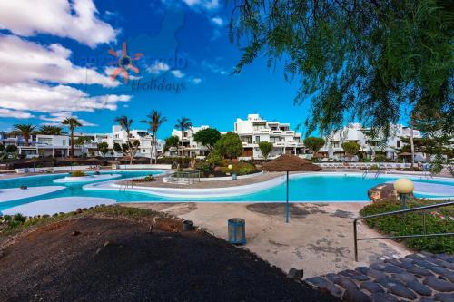 a swimming pool at a resort with white buildings at Vivienda Vacacional Los Molinos 6205 in Costa Teguise