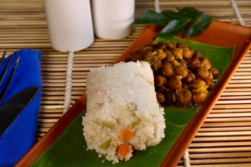 a green plate with a piece of rice and some food at AyurSoma Ayurveda Royal Retreat in Kovalam